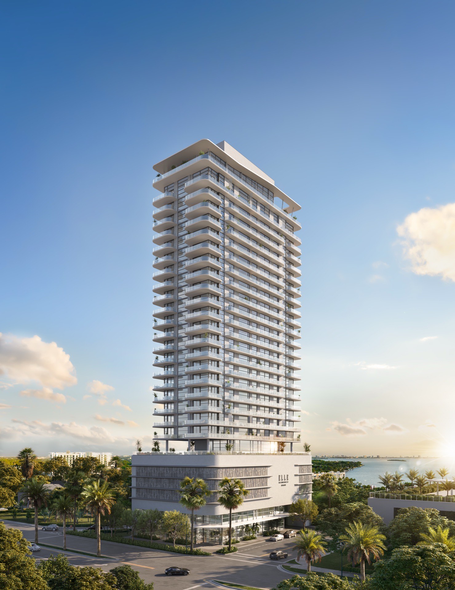 ELLE Residences Miami, full tower view from street level showing curved white balconies and palm-lined entrance